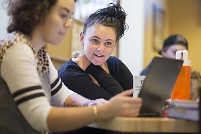 Student works at laptop while other student looks on