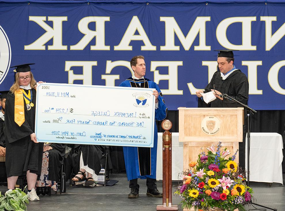 Student PJ Dudinetz at podium making remarks while President 彼得伊甸园 and student Eden Kayser hold oversized check 